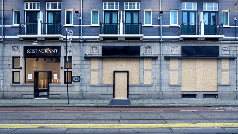 Empty and boarded-up storefronts with apartments above them.